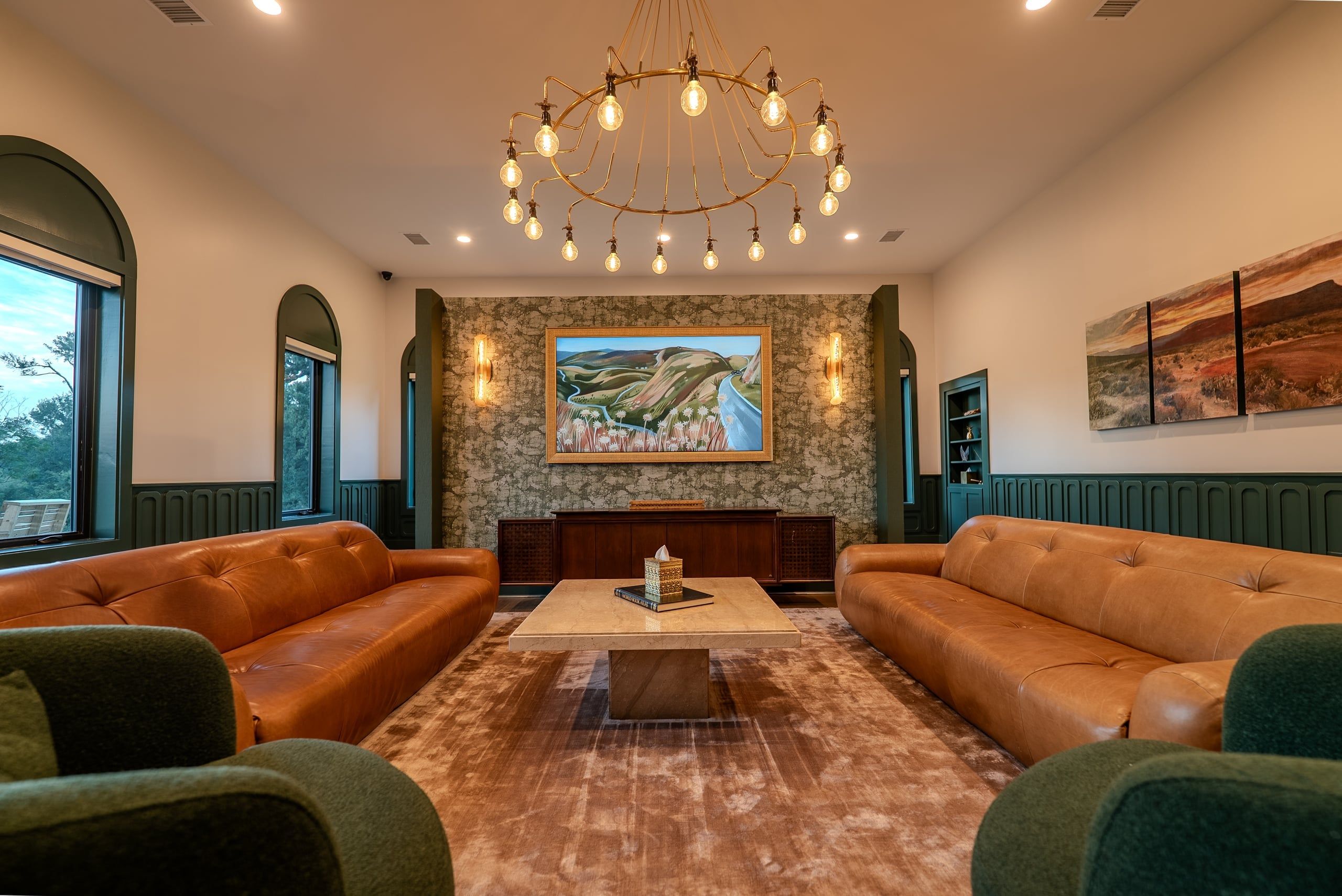 A warm, private family lounge at the Elgin facility with leather seating, soft light, and original Texas landscape art